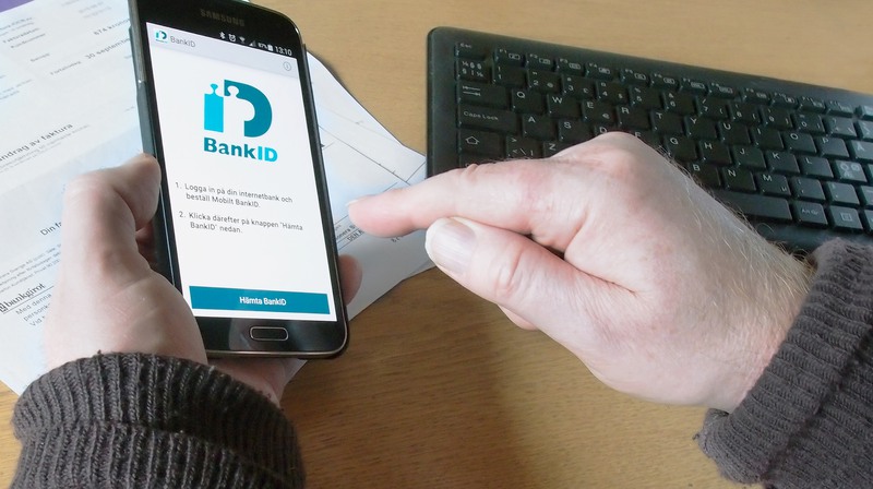 Person som betalar en faktura med mobilt Bank-id
