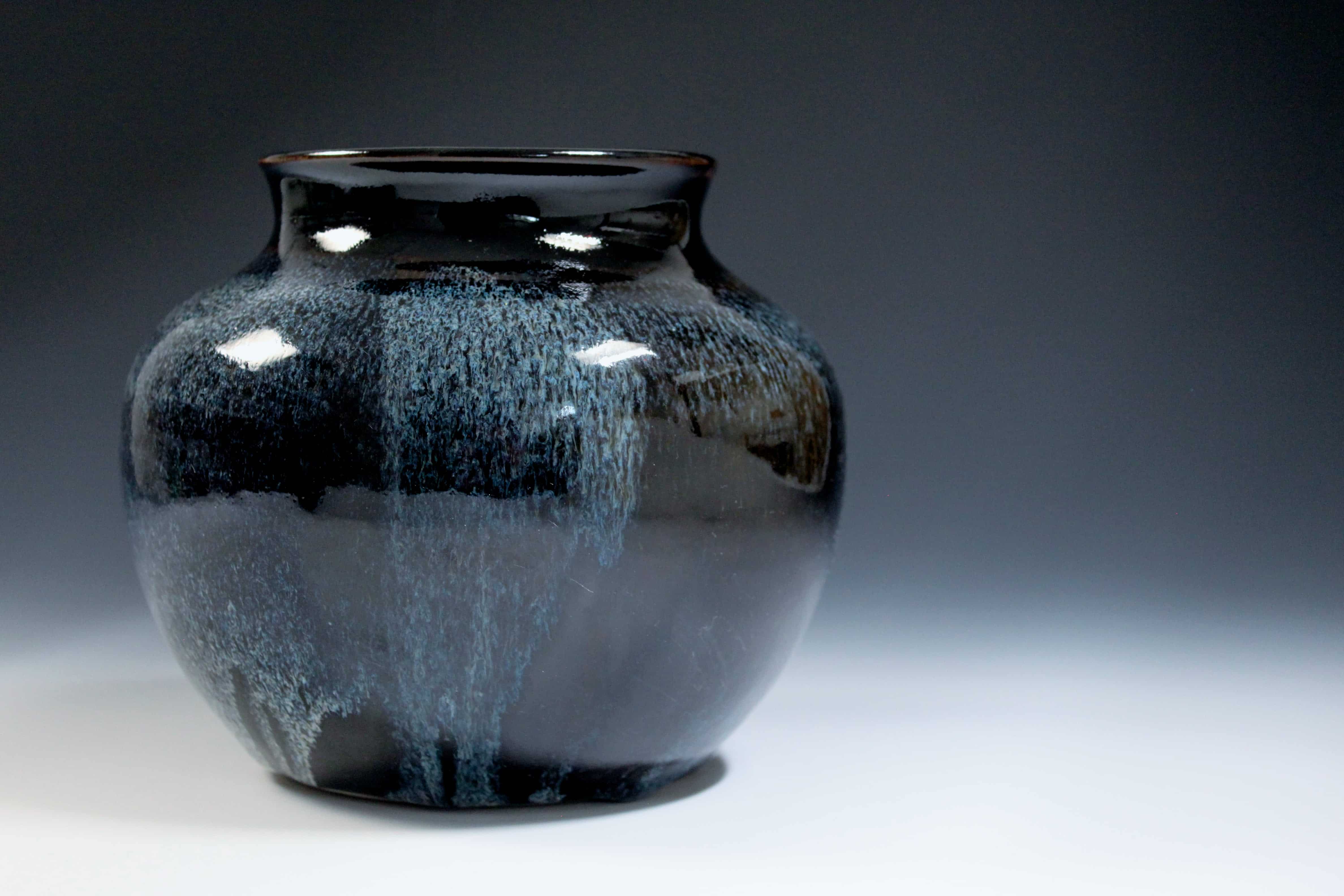 Fotografi av keramikvas med spräcklig glasyr i blått och mörkgrönt.