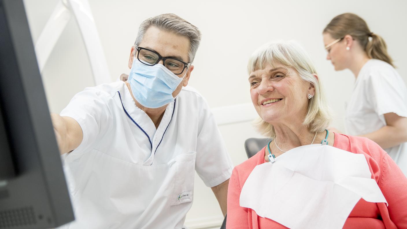 Tandläkare och patient vid dator