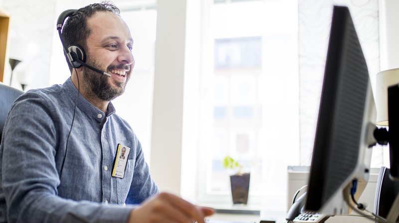 Tolk sitter med headset vid ett skrivbord framför en datorskärm