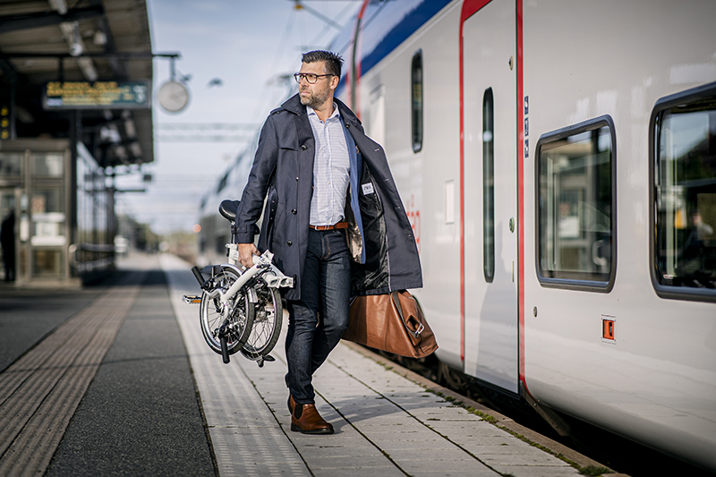 En man går med en vikcykel i handen på en tågperrong.