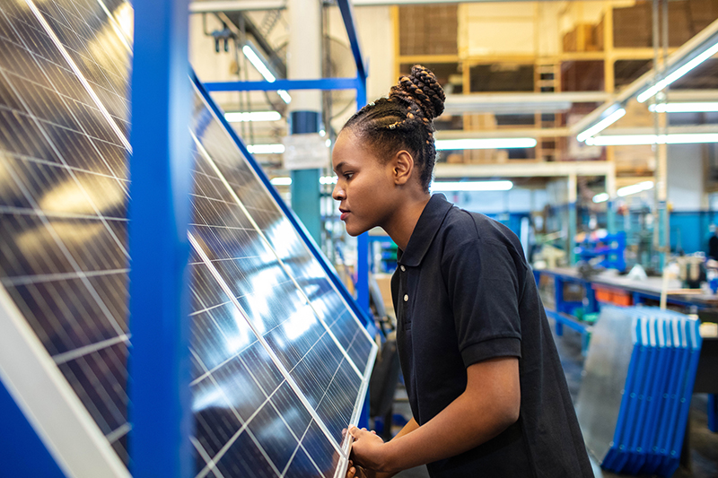 En kvinna arbetar i en fabrik där man tillverkar solpaneler