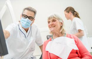 Tandläkare och patient vid dator