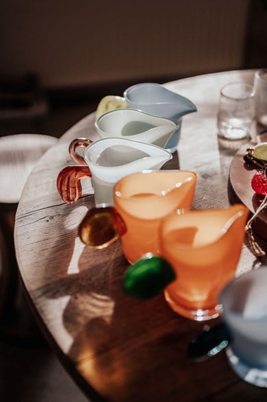 Fotografi av glasskulpturer i form av små kannor med platta öron, Vitt, brunt, grön, aprikos.
