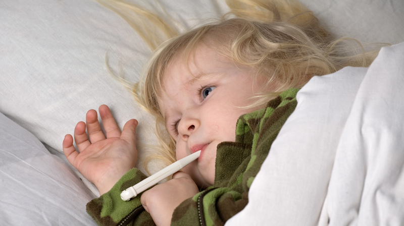 Litet barn med feber som ligger nedbäddat i sängen