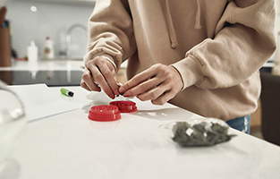 En rund plastdosa för att finfördela cannabis i innan man rullar en joint.