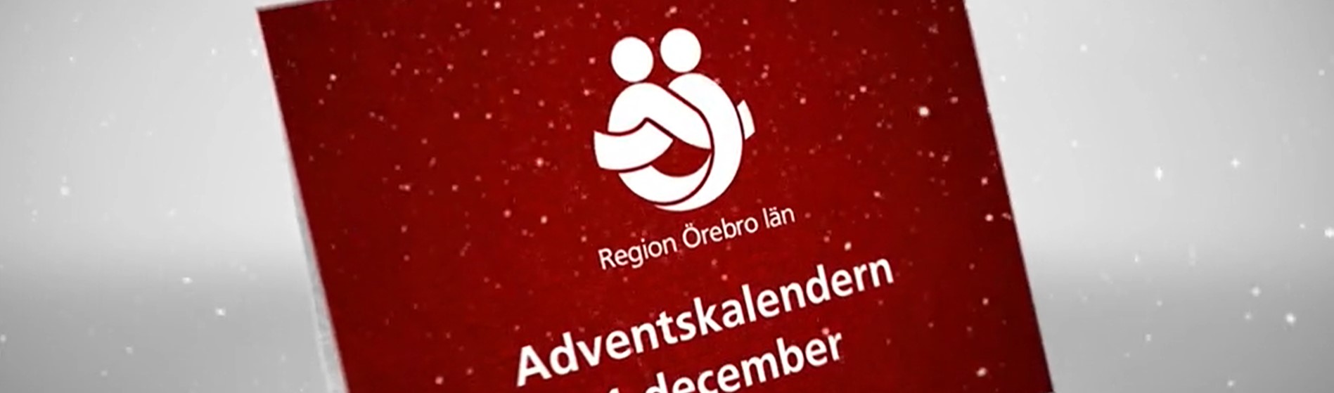 Snö singlar ner på ett rött kort med texten Region Örebro län adventskalender