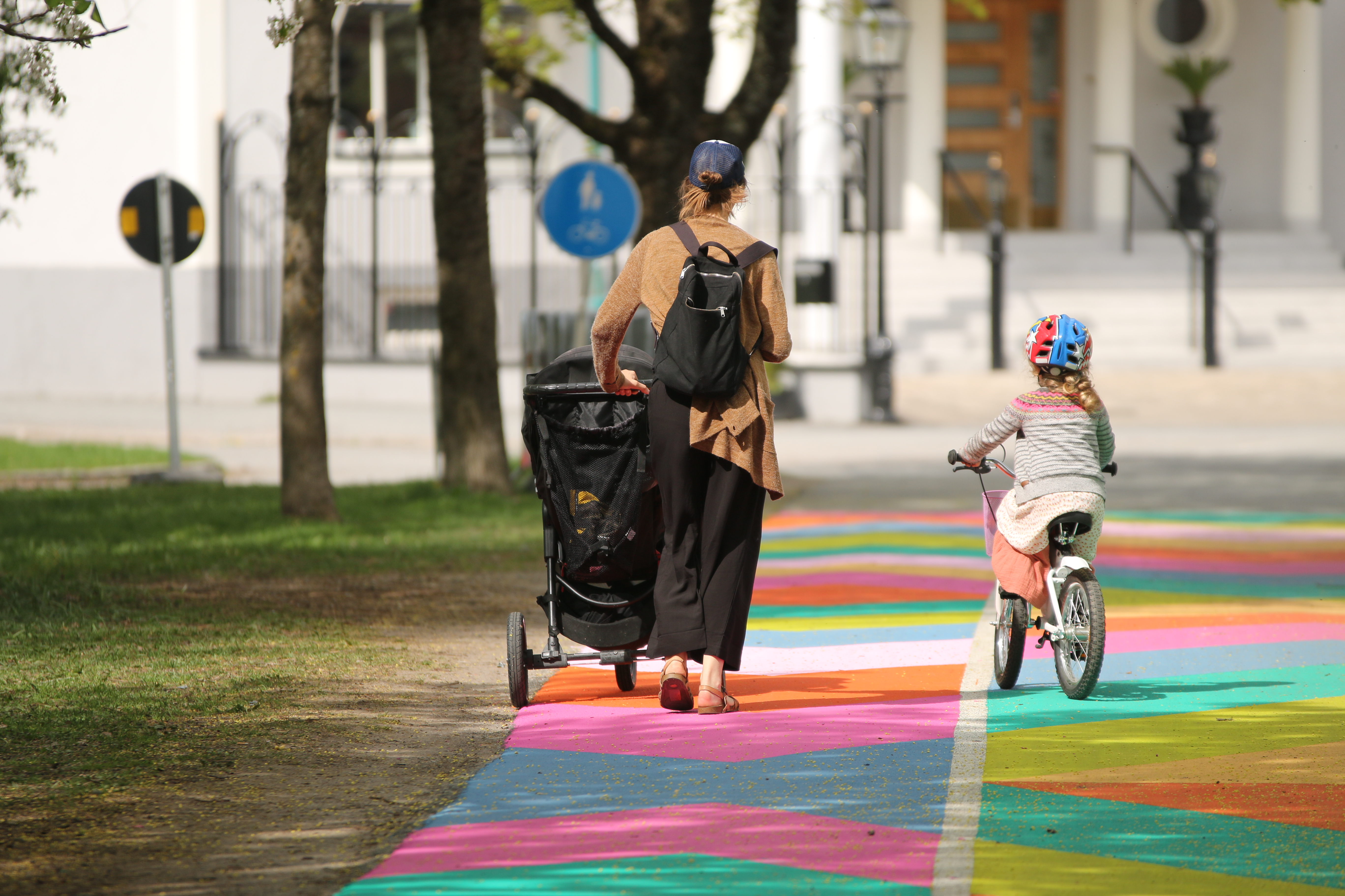 Mamma och barn går och cyklar på en färgglad väg