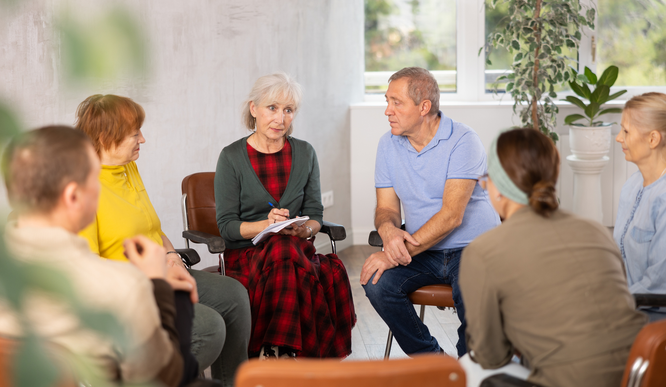 En kvinna för ett samtal inomhus med personer runtomkring sig