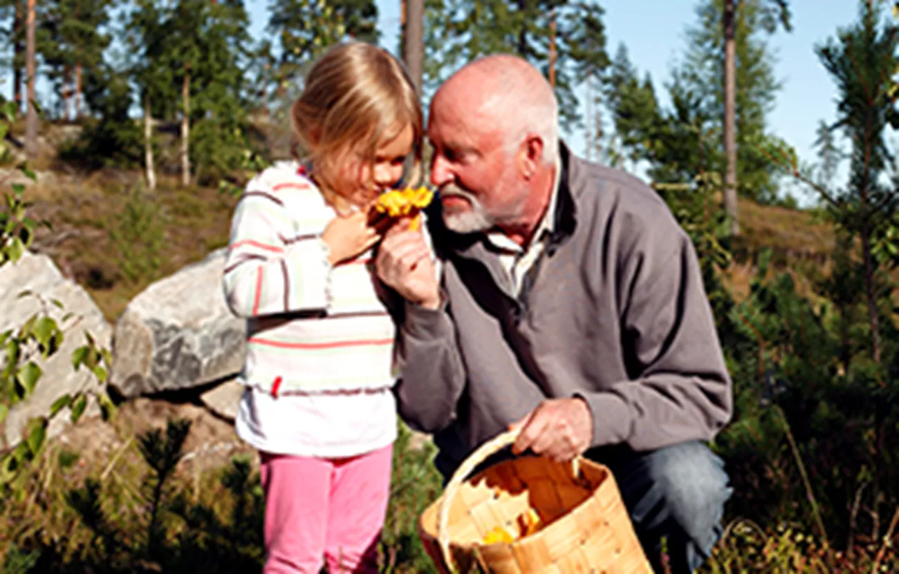 En man och ett barn i skogen med en svampkorg.