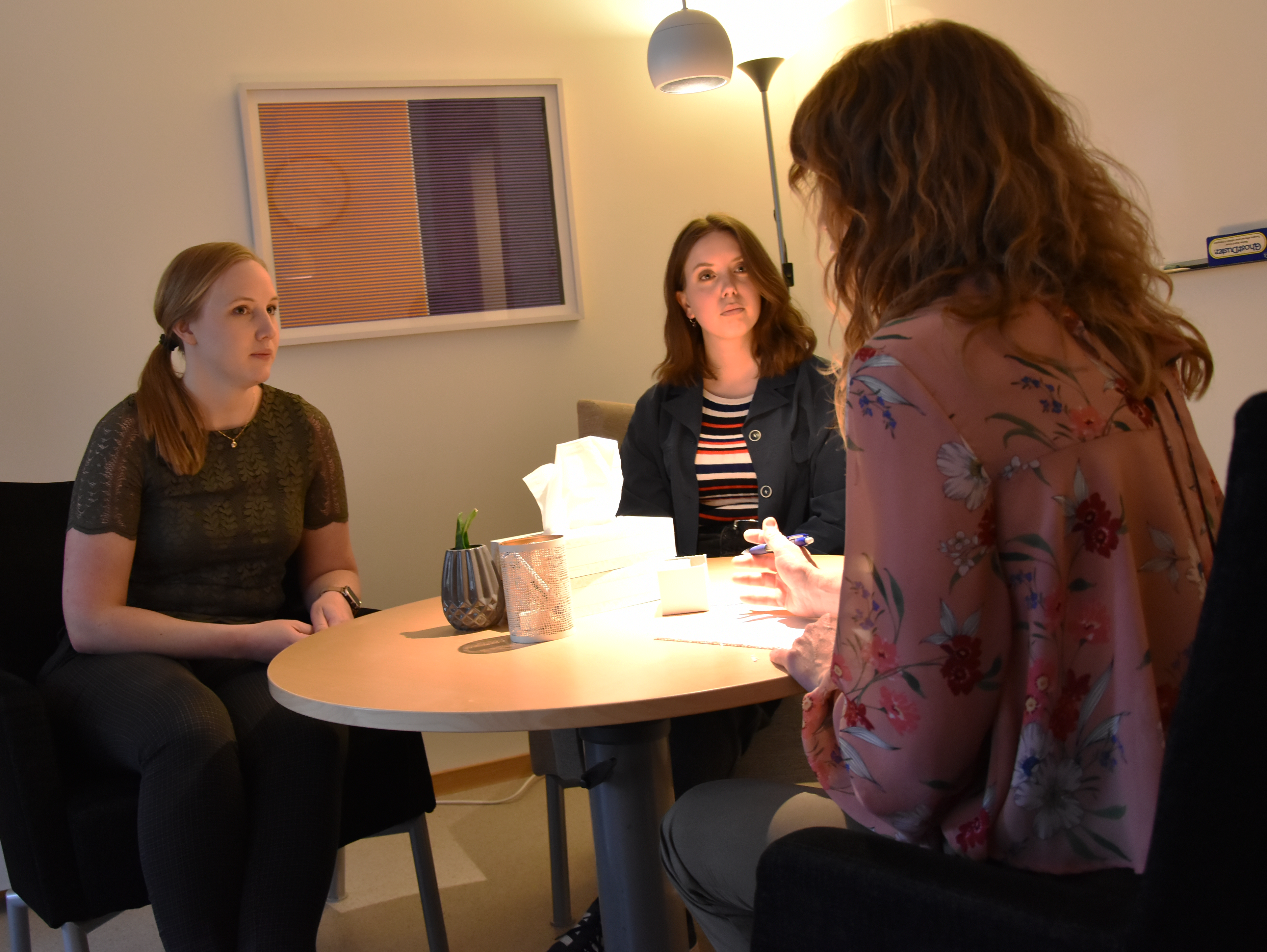 Tre personer sitter kring ett runt bord