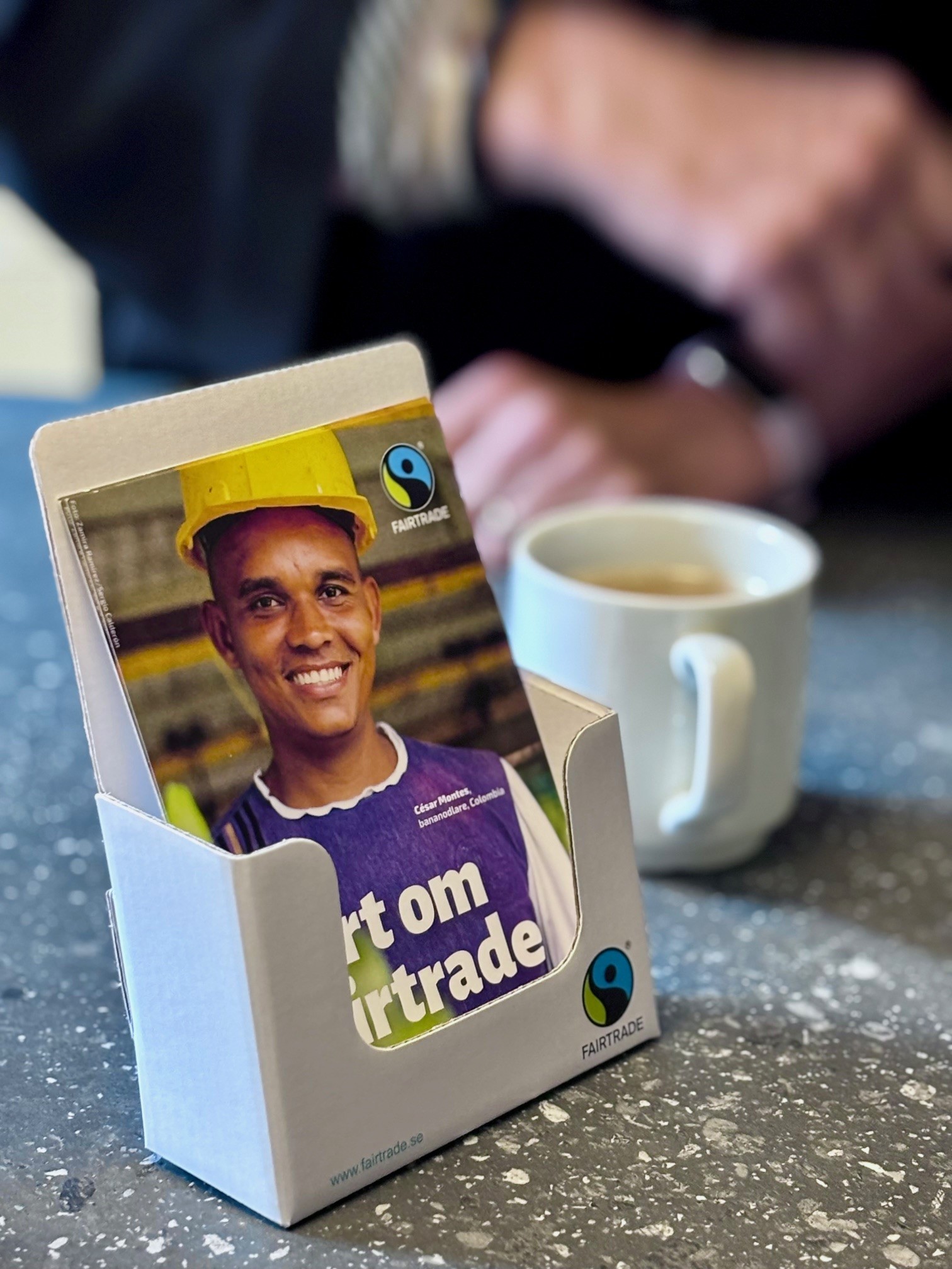 Broschyrställ med kaffekopp i bakgrunden