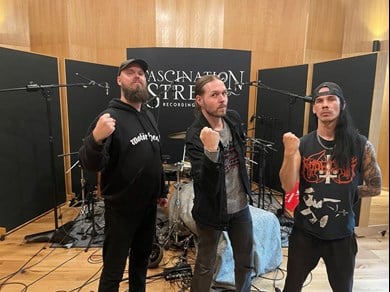 Tre personer framför trumset i musikstudio