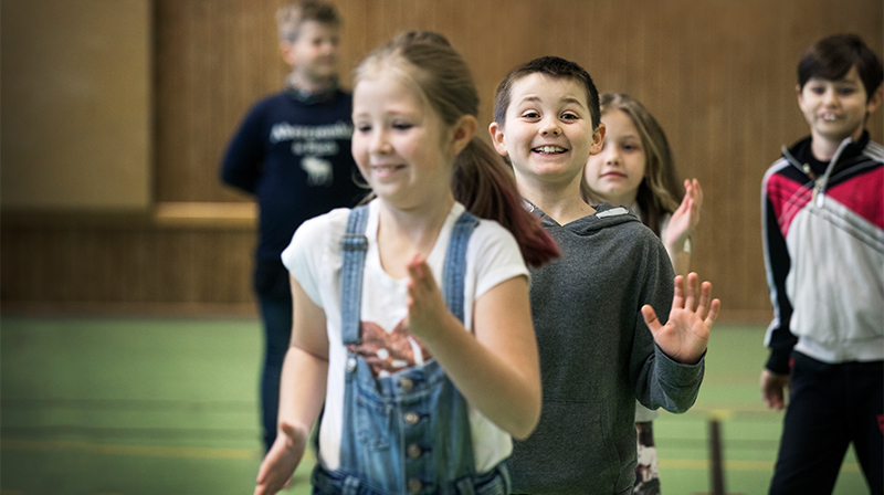 Glada barn som dansar i en idrottshall
