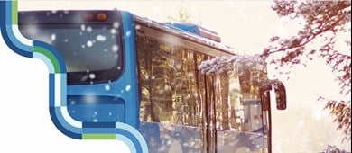 En buss och snöiga granar. Länstrafikens dekorelement i kanten av bilden