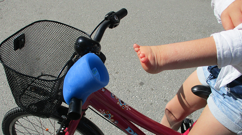 Barnhand med dysmeli som har ett hjälpmedel för att hålla i cykelstyret.