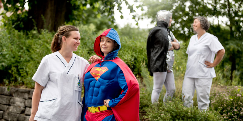 Tandvårdspersonal står utomhus och pratar med två superhjältar